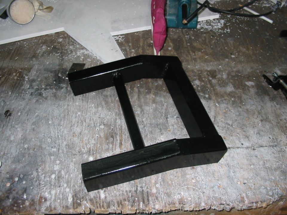 Black metal part on a workbench with Supermotors.net logo