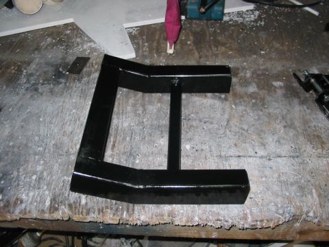 1985 Ford Crown Victoria LTD - A black metal bracket sits on a workbench, possibly a custom part or repair component.