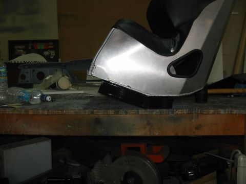 1985 Ford Crown Victoria LTD - A racing seat is shown on a workbench, with various car parts and bottles scattered around.
