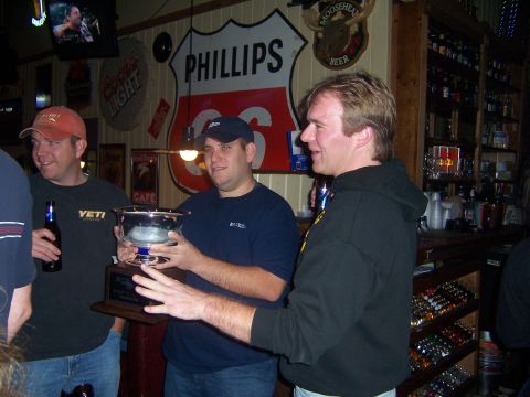 1985 Ford LTD Crown Victoria - Men celebrate with a trophy in a bar decorated with vintage signs.