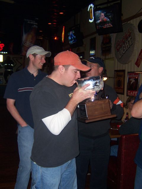 1985 Ford LTD Crown Victoria - A group of friends celebrates with a trophy in a dimly lit bar.