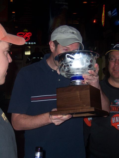 1985 Ford LTD Crown Victoria - A man holds a large trophy, possibly after a hockey game, as others look on.