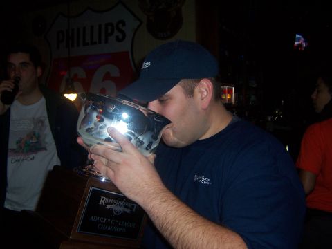 1985 Ford LTD Crown Victoria - A man drinks from a large trophy, celebrating his team's championship win in the Adult C League.