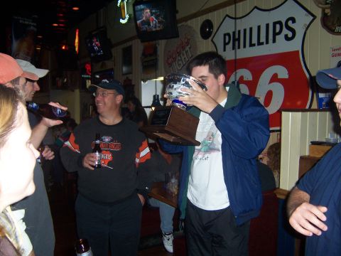 1985 Ford LTD Crown Victoria - Friends celebrate with a trophy in a bar, with vintage signage on the wall.