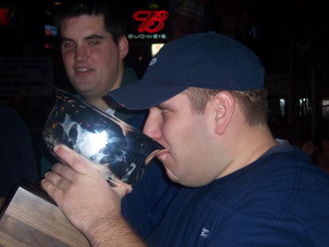 1985 Ford LTD Crown Victoria - A man drinks from a trophy in a bar setting with a Budweiser sign visible.