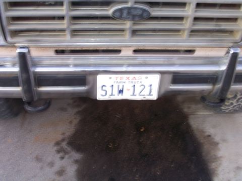 1982 Ford Bronco - Close-up of a truck's grille and bumper, a Texas Farm Truck license plate.
