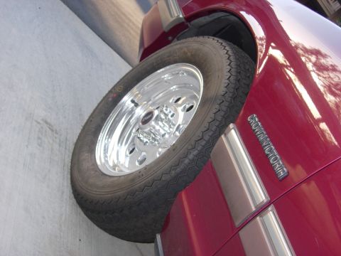 1992 Ford Crown Victoria - Close-up of a red vehicle's side, showing a chrome wheel and fender trim.