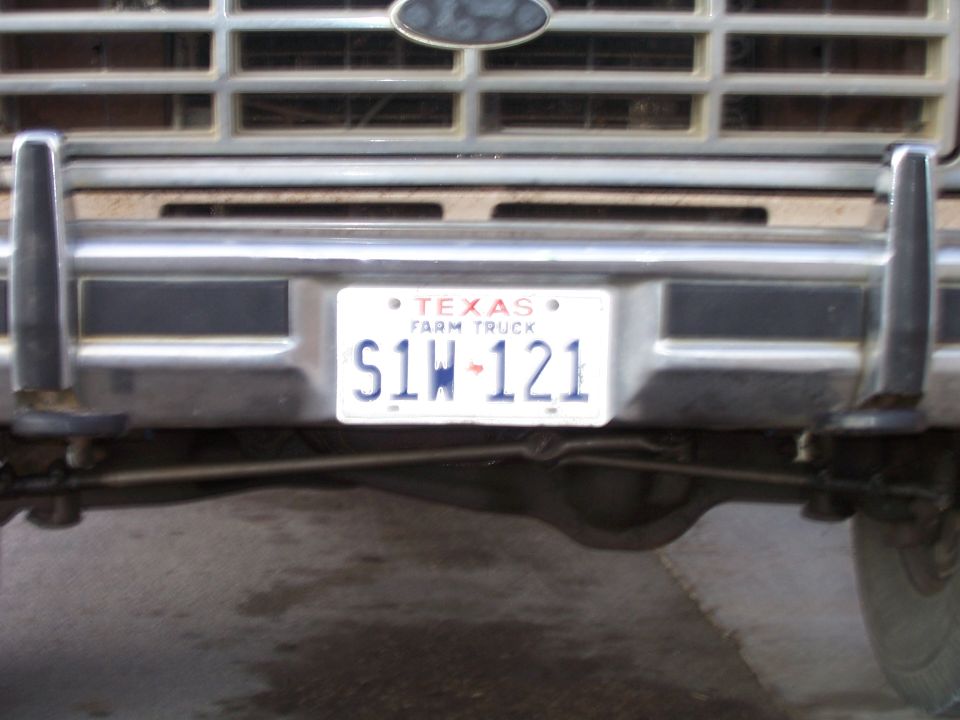 Front bumper and grille of a Ford truck with a Texas Farm Truck license plate