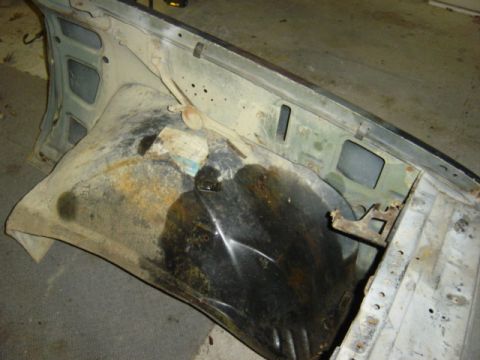 1987 Suzuki Samurai - This image shows the interior of a vehicle's fender well, revealing significant rust and dirt accumulation.