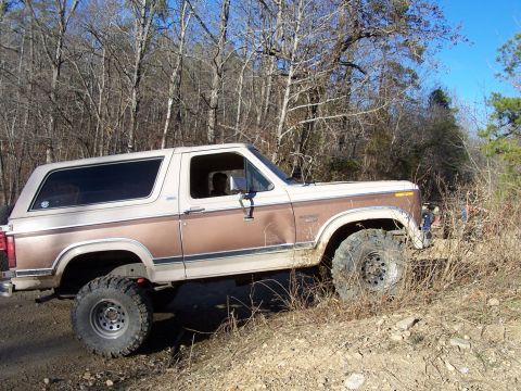 1982 Ford Bronco - This lifted 1980 Ford Bronco navigates an off-road trail with a two-tone brown and cream paint scheme.