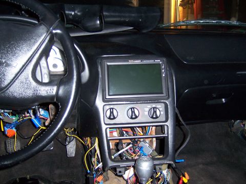 1997 Ford Probe - The dashboard of a car is shown with the center console disassembled, revealing numerous wires and an aftermarket display unit.