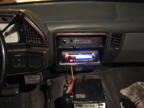 1990 Ford Bronco - aftermarket CD stereo head unit with red and blue illumination is installed in a vehicle's dashboard above older gauges.