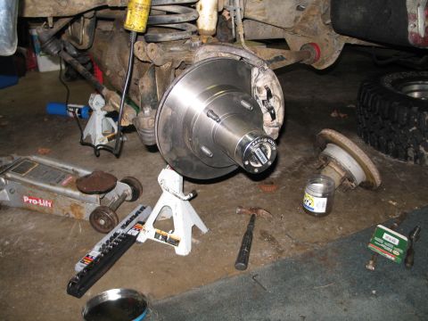 1995 Ford Bronco - Front wheel hub assembly with new rotor and WARN locking hub, tools on floor during repair.