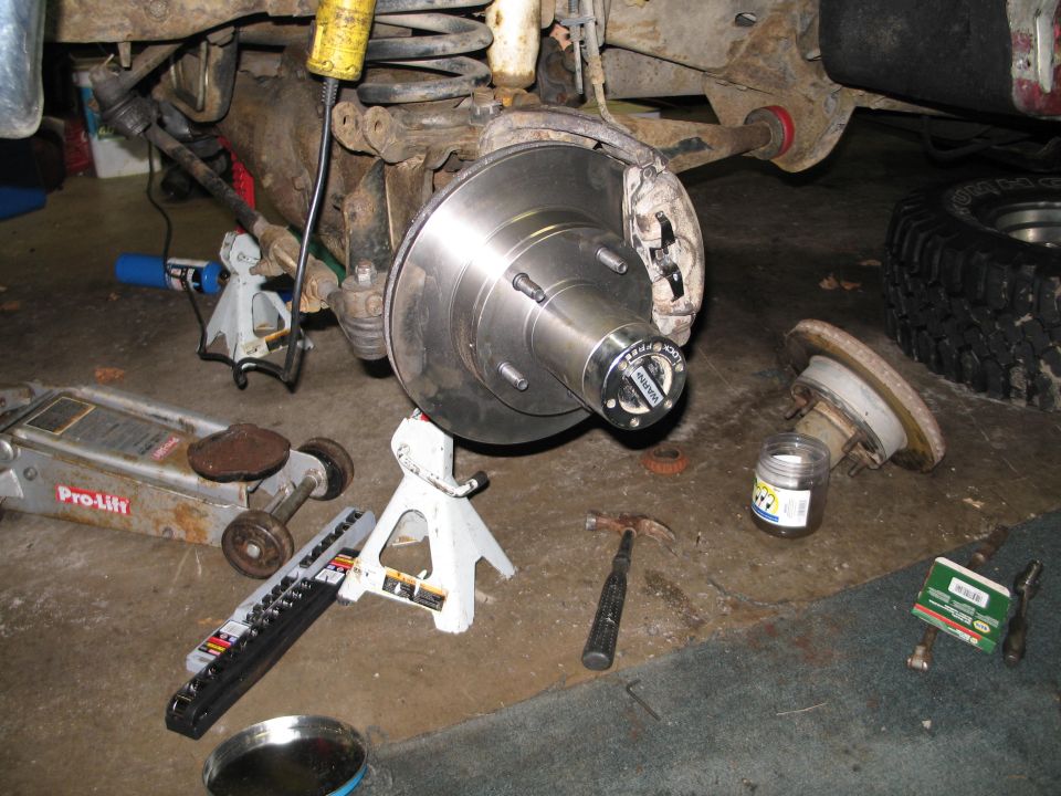 Front wheel hub assembly with new rotor and WARN locking hub, tools on floor