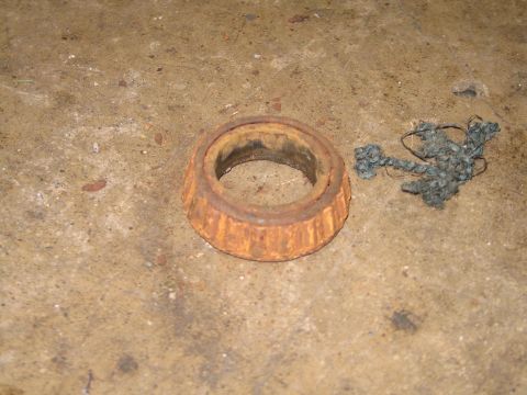 1995 Ford Bronco - A heavily rusted wheel bearing lies on a concrete surface next to a piece of tangled string.