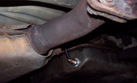1985 Ford Crown Victoria LTD - Underside view of a vehicle's exhaust system and oil pan, showing an oxygen sensor.