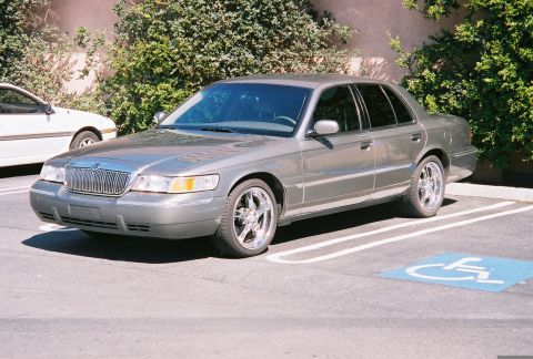2000 Mercury Grand Marquis - This sedan is parked in a handicapped spot next to some greenery.