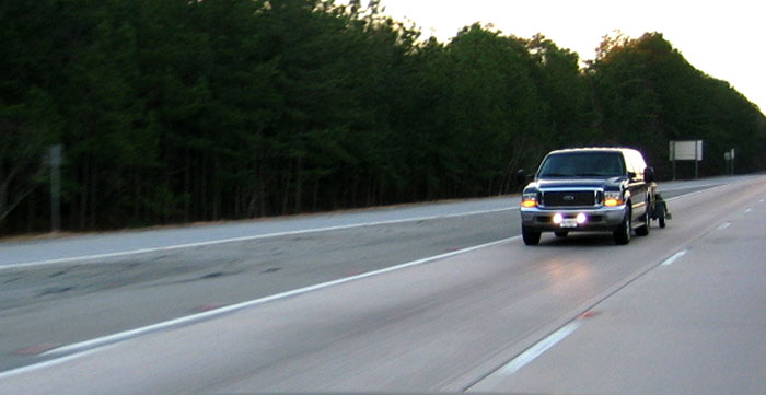Dark blue 2002 Ford Excursion towing a trailer on highway