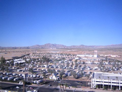 1990 Ford Bronco - Elevated view over a sprawling desert RV park of parked motorhomes, with low mountains on the horizon under a clear sky.