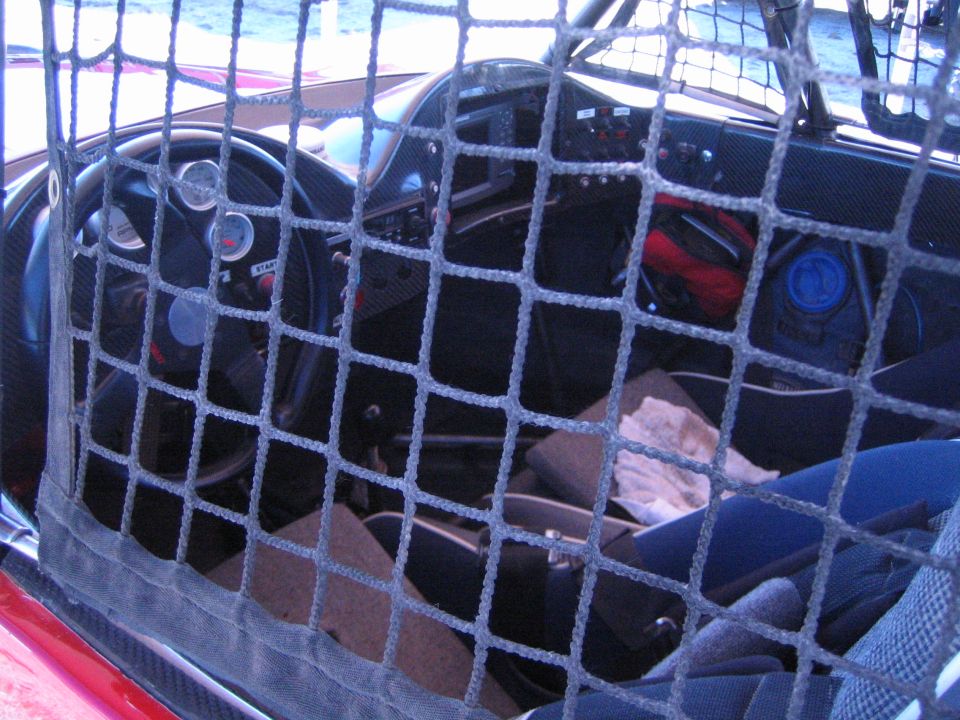 Cockpit of an off-road race car seen through a black window net