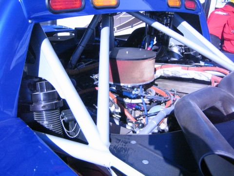 1990 Ford Bronco - rear engine bay of a blue tube-chassis off-road buggy, showing a round air filter, exhaust headers and the white roll cage tubing.