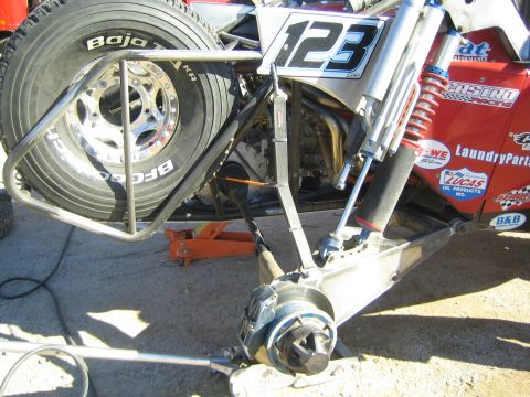 1990 Ford Bronco - Close-up of an off-road race truck's front suspension, coilover shock and a BFGoodrich tire, with race number 123 on a panel.