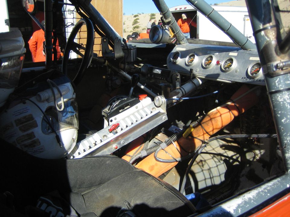 Interior of a tube-chassis race truck showing gauges and roll cage