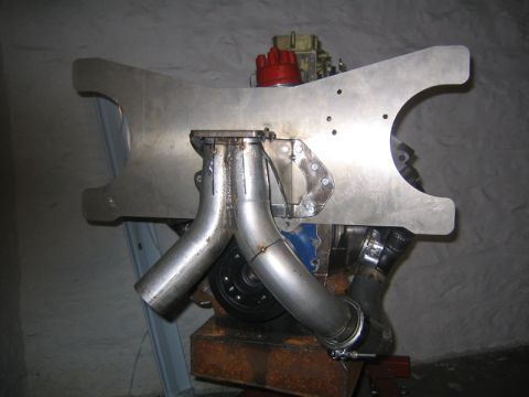 1969 Ford Mustang - A custom exhaust manifold is attached to an engine block, polished metal pipes and a large fabricated plate.