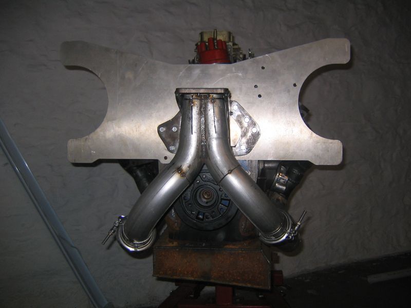 Engine with custom exhaust pipes and a red carburetor, mounted on a stand