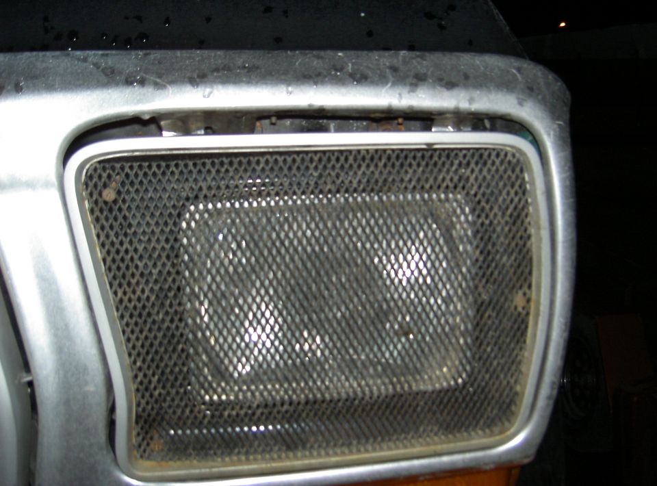 Close-up of a vehicle's headlight assembly covered by a diamond-patterned mesh grille