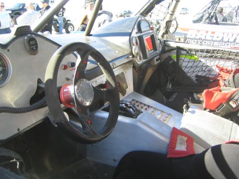 1990 Ford Bronco - Cockpit of a Baldwin Motorsports race truck showing a carbon-look steering wheel, gauges and switch panel.