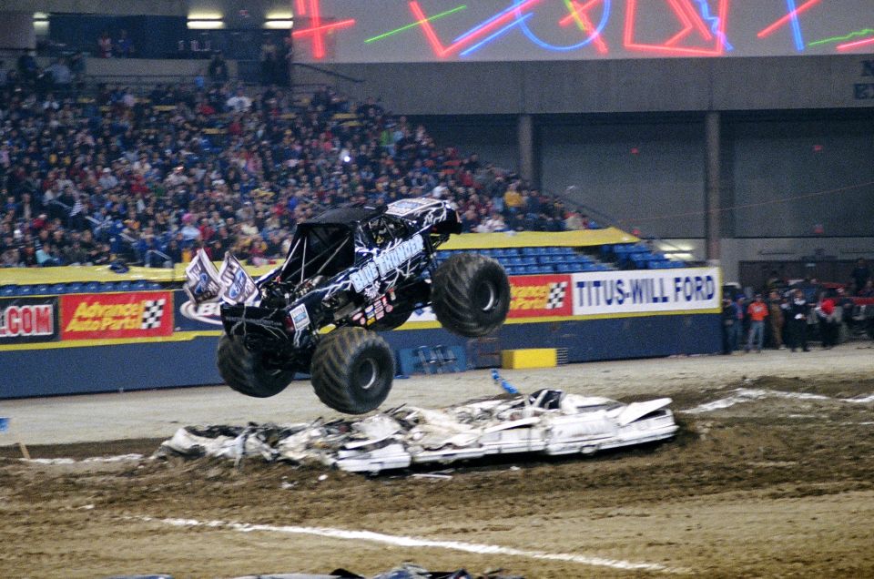 Monster truck mid-air over crushed cars, "Blue Thunder" visible on side