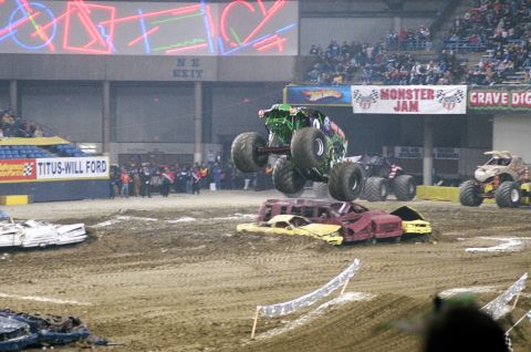 1976 Ford F-150 - A monster truck performs a jump over a pile of wrecked cars during an event.