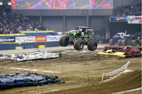 1976 Ford F-150 - A monster truck jumps over crushed cars during a competition in an arena.