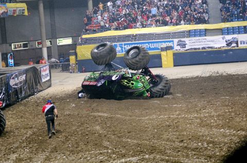 1976 Ford F-150 - A monster truck lies on its side during an event, with spectators watching from the stands.