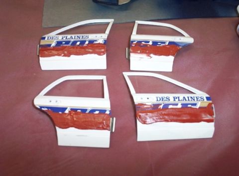 1998 Ford Crown Victoria - Four doors, likely from a police vehicle, are shown with red paint applied to their lower sections.