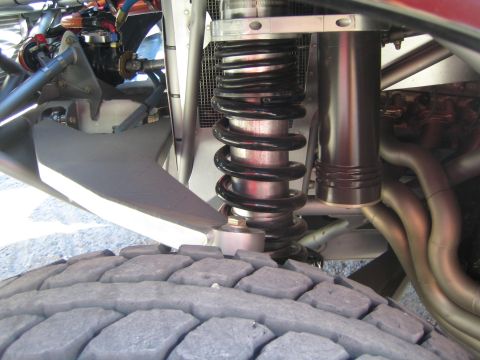 1990 Ford Bronco - Detail of a long-travel coilover shock and tube suspension mounted above a worn off-road tire on a race truck.