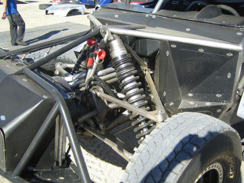 1990 Ford Bronco - Bare tube-frame rear suspension of an off-road race vehicle showing twin coilover shocks, bypass shocks and a BFGoodrich tire.