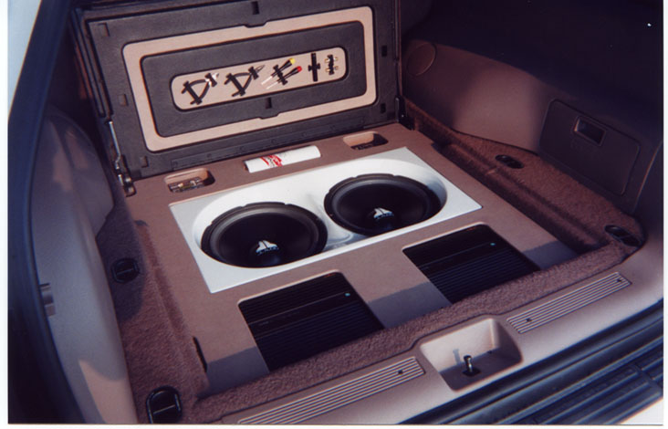 Car trunk with two JL Audio subwoofers and amplifiers installed, carpeted interior