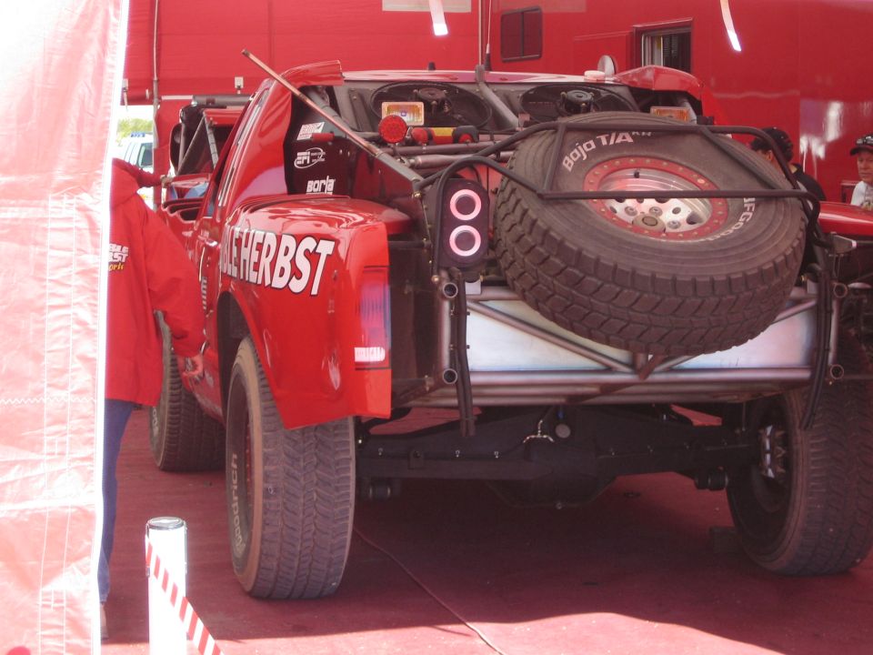Rear bed of red Terrible Herbst off-road race truck with mounted spare tire