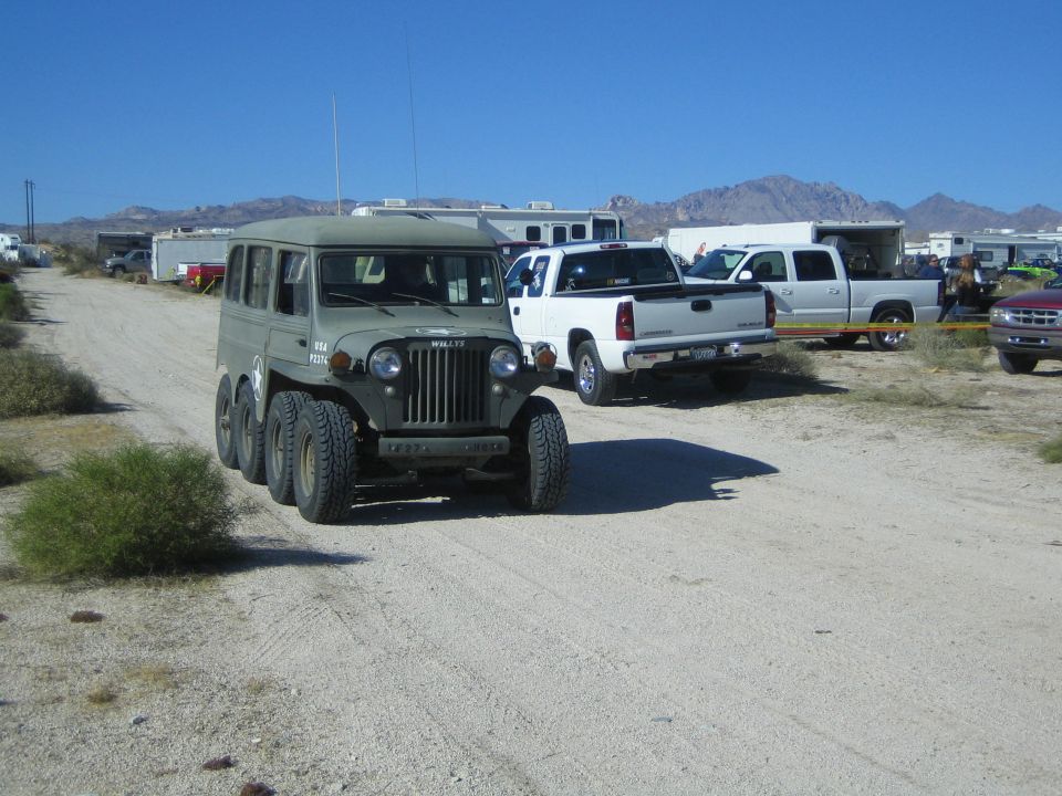 Olive-drab six-wheeled Willys military vehicle on a desert dirt road