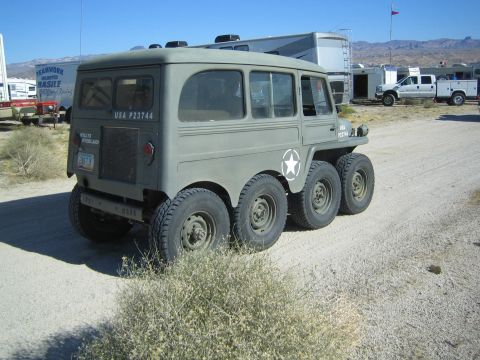 1990 Ford Bronco - Rear three-quarter view of an olive-drab six-wheeled Willys Overland military vehicle marked USA P23744 with a white star, parked on dirt.