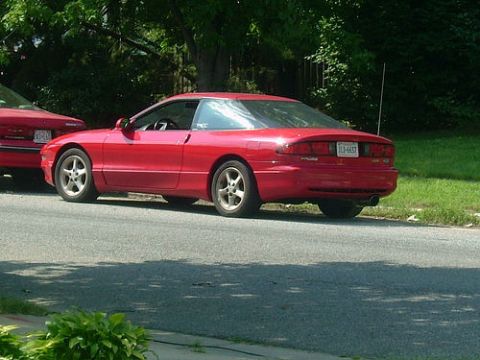 1993 Ford Probe - A red 1993 Ford Probe is parked on the side of the road with another vehicle beside it.
