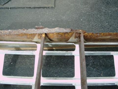 1966 Ford F-250 - A close-up view of a heavily rusted metal piece positioned above a white grille with dark square openings.