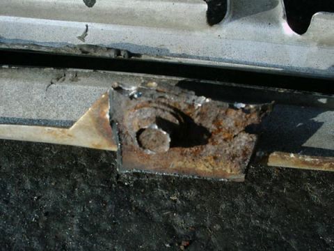 1966 Ford F-250 - Rusted metal bracket with a bolt, likely a vehicle part.