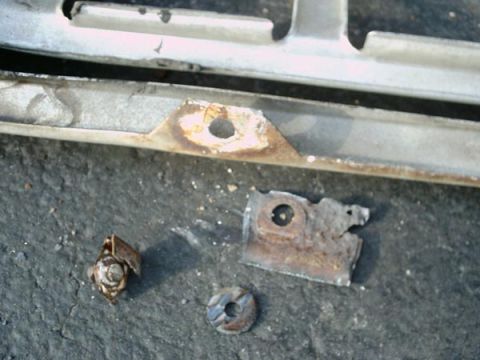1966 Ford F-250 - Close-up of a damaged metal grille piece with associated hardware, showing signs of corrosion.