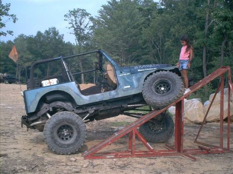 2005 Ford Excursion - A blue Jeep Wrangler is positioned on a metal ramp, with 'Wrangler' and 'Rock Crawler' text visible on its hood.