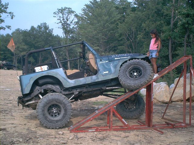 Blue Jeep Wrangler on a ramp with 'Wrangler' and 'Rock Crawler' decals
