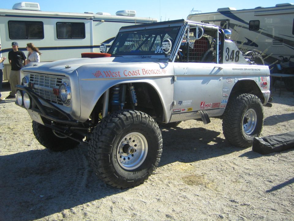 Silver early Ford Bronco race truck #348 West Coast Broncos in desert pits