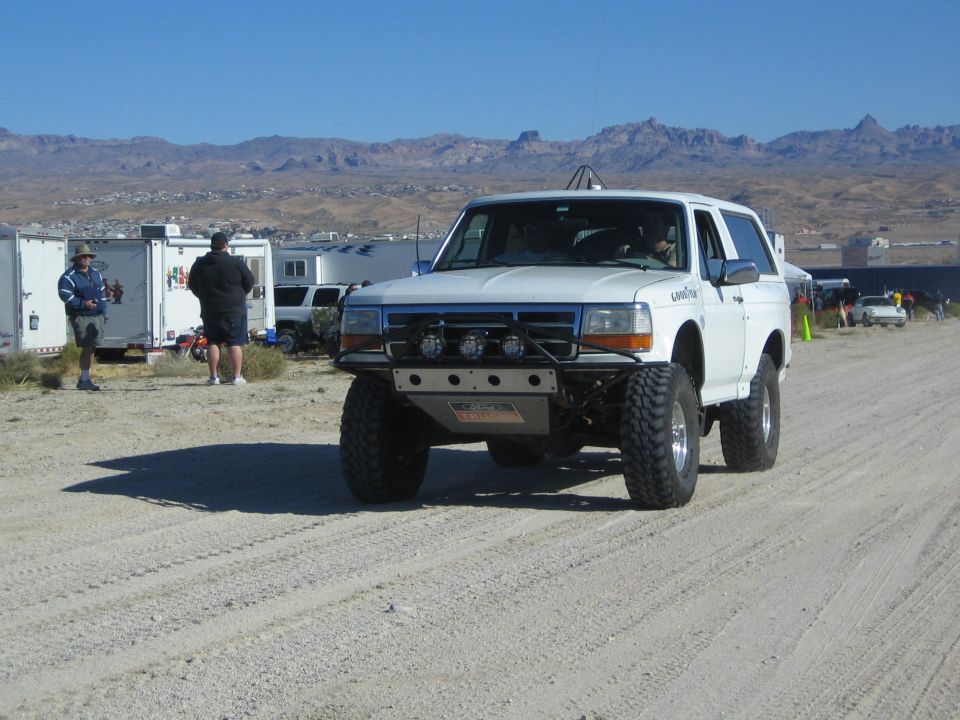 White lifted Ford Bronco off-road truck on desert dirt road near pits